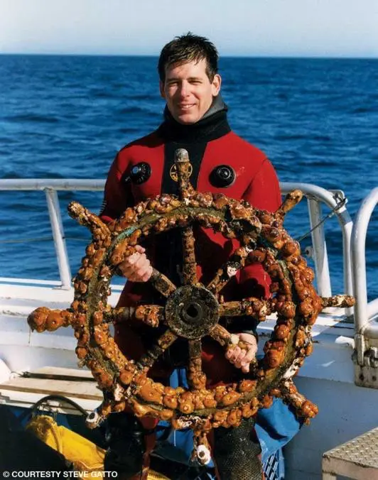 A man holding on to the steering wheel of a boat.