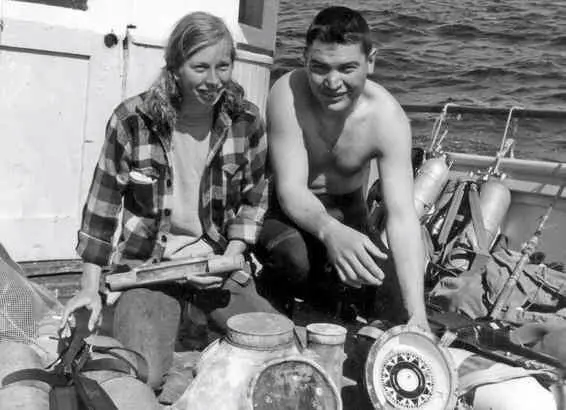 A man and woman sitting on the deck of a boat.