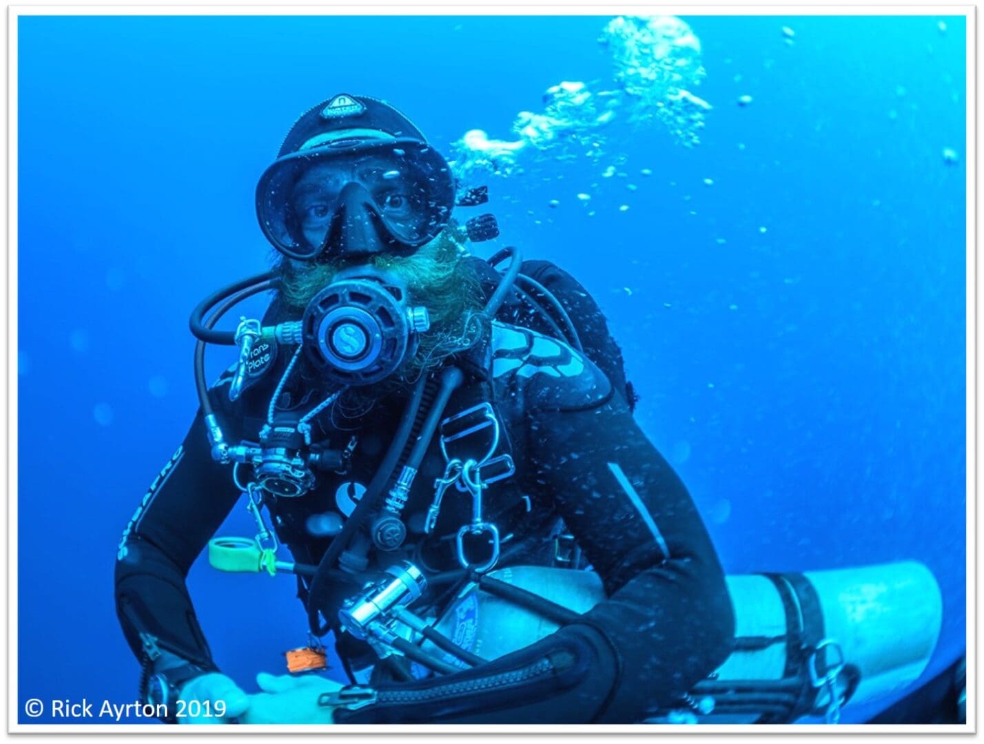 A scuba diver in a black suit and helmet