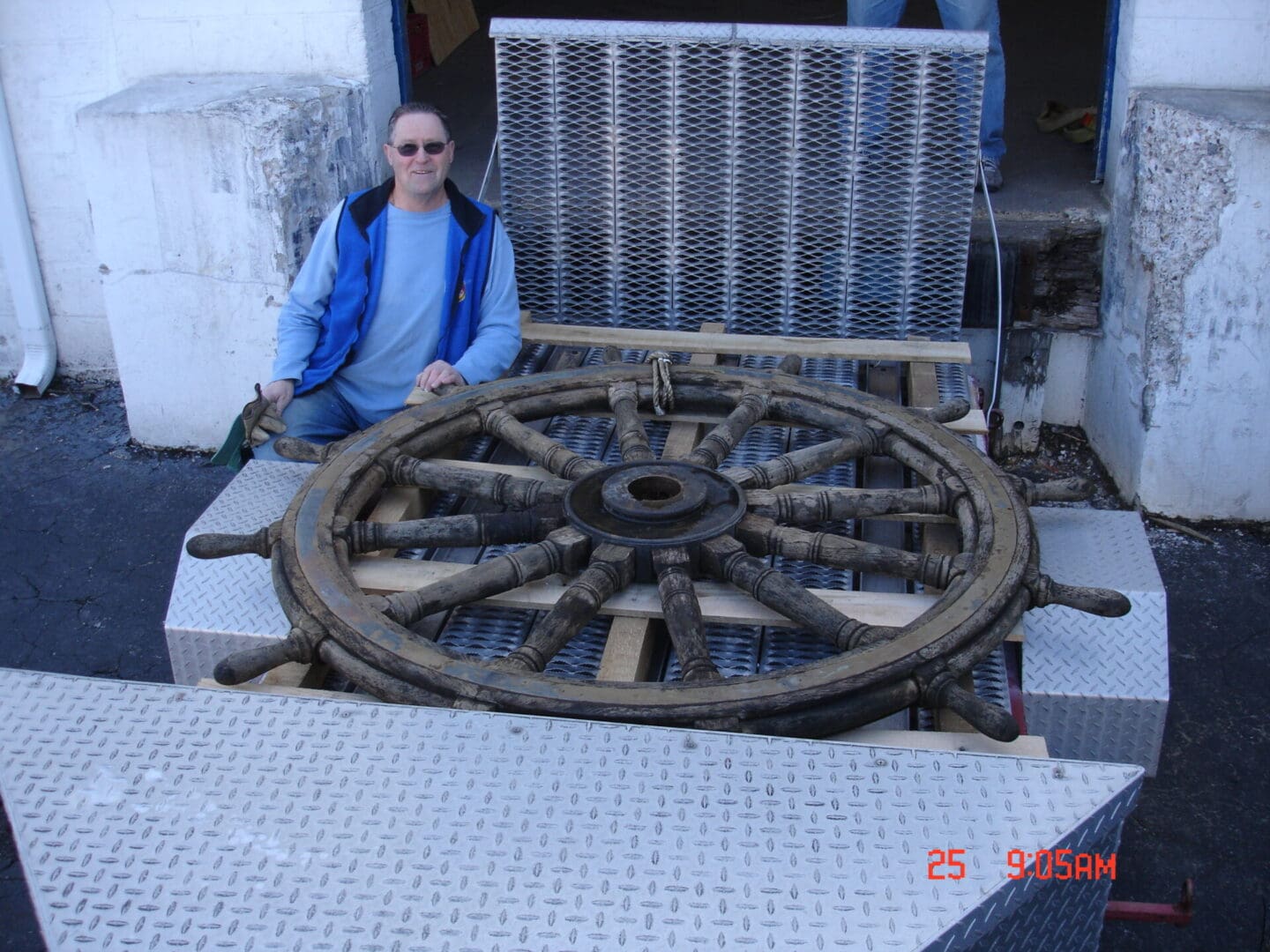 A man sitting on top of a wooden wagon wheel.