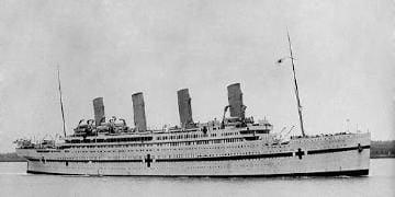 A large ship with four sails on the water.