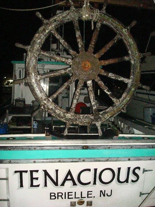 A large wheel on the back of a boat.