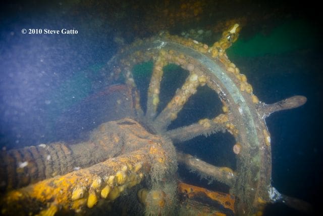 A large wheel is sitting in the water.