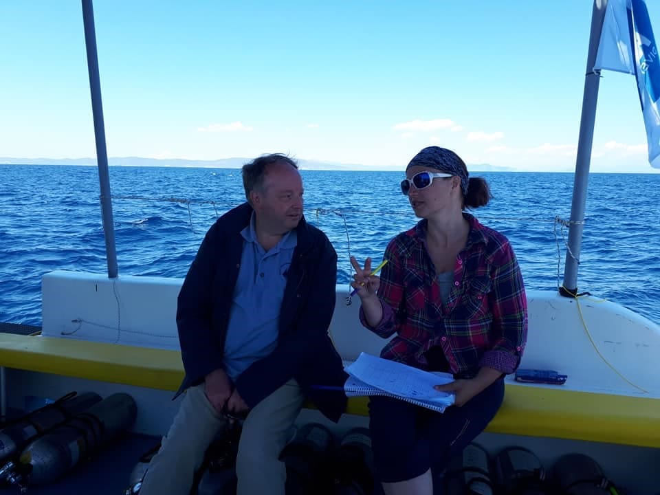 Two people sitting on a boat in the ocean.