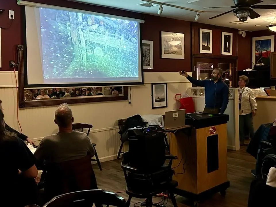 A man standing in front of a projector screen.