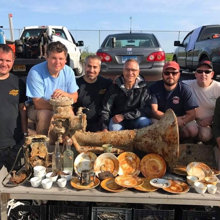 A group of men standing around a table with food.